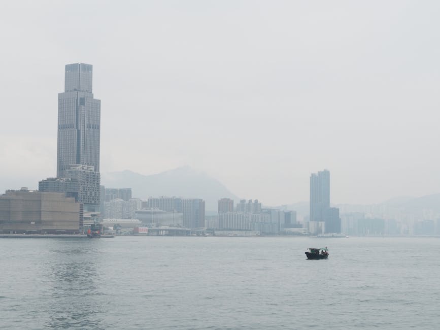 Serene view of a boat floating on Hong Kong Harbor with a city skyline backdrop.