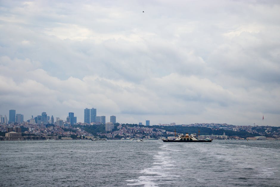 Ferry sailing on the Bosphorus with Istanbul's skyline in the background, cloudy day.