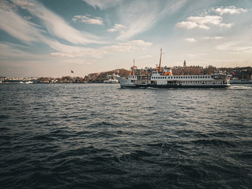 A scenic view of a ferry boat crossing the Bosphorus in Istanbul under a clear, sunny sky.